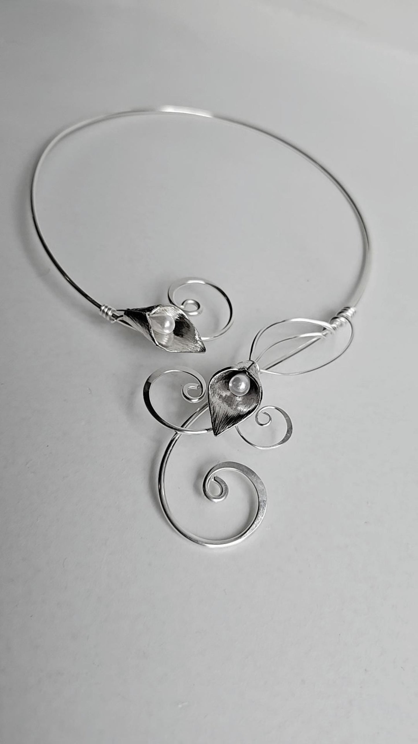 Handcrafted silver-plated Calla Lily torc necklace with two faux pearl centers, featuring elegant hammered wire curls and an open-back collar design.