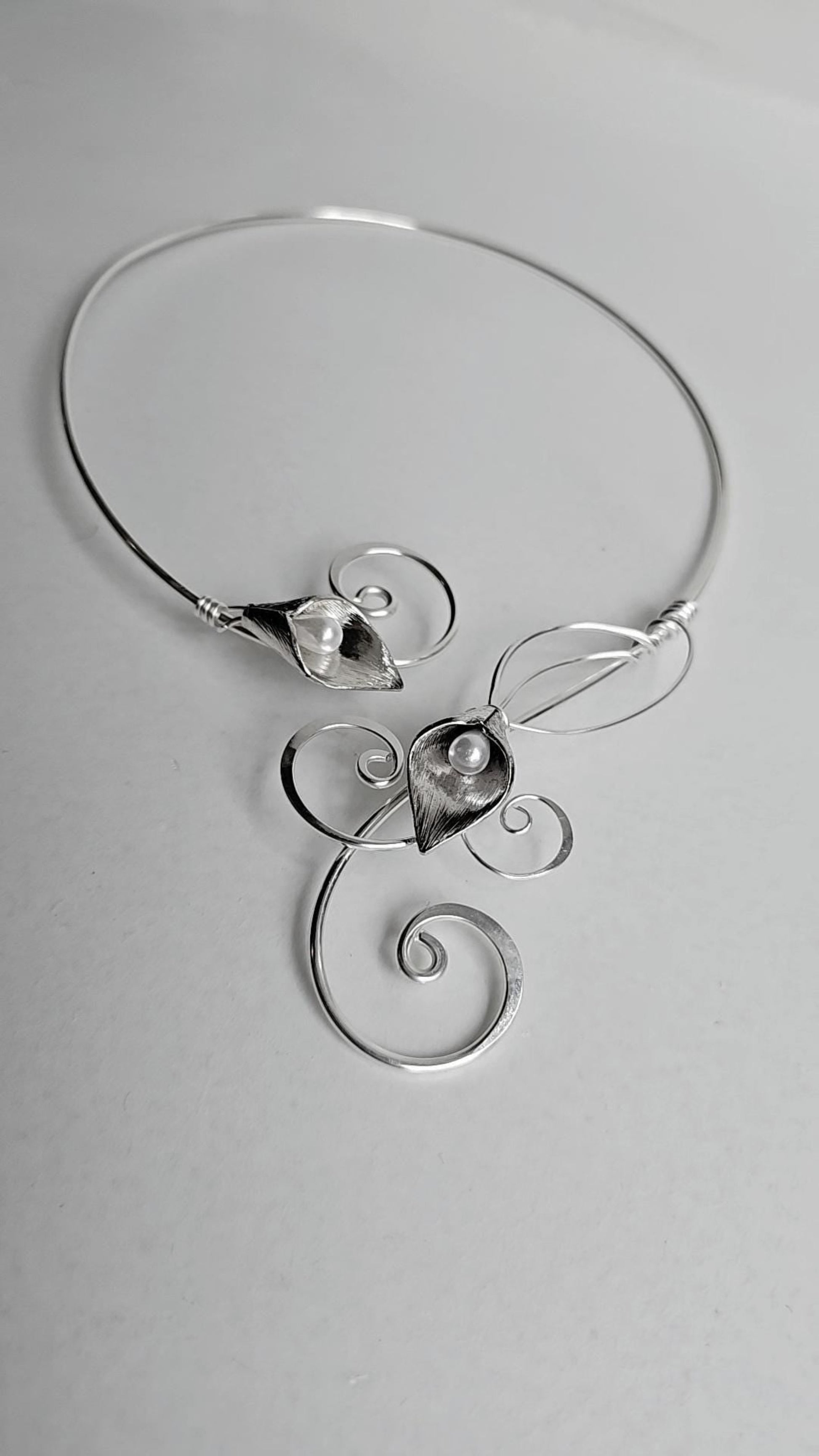 Handcrafted silver-plated Calla Lily torc necklace with two faux pearl centers, featuring elegant hammered wire curls and an open-back collar design.