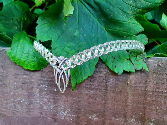 Sterling silver-plated elven tiara with a Celtic knot V-shape design, displayed against vibrant green leaves for a woodland aesthetic.